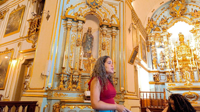 Professora Danielle explicando conceitos da arte barroca dentro de Igreja visitada pelo grupo.